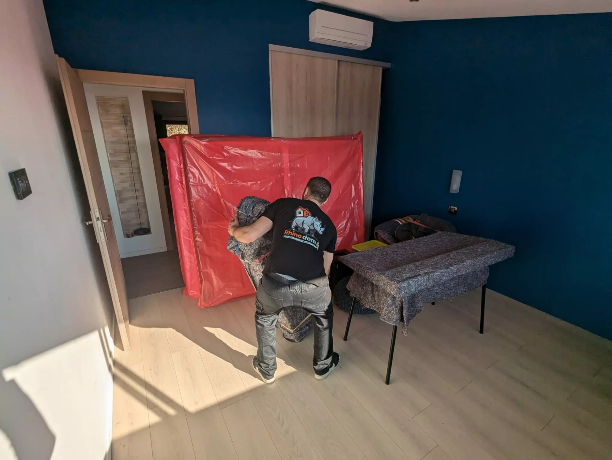 Un déménageur rhinodem emballe un meuble