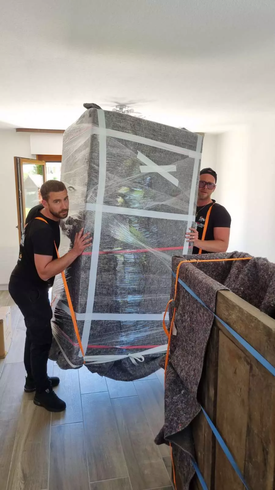 Deux déménageurs portent un gros meuble