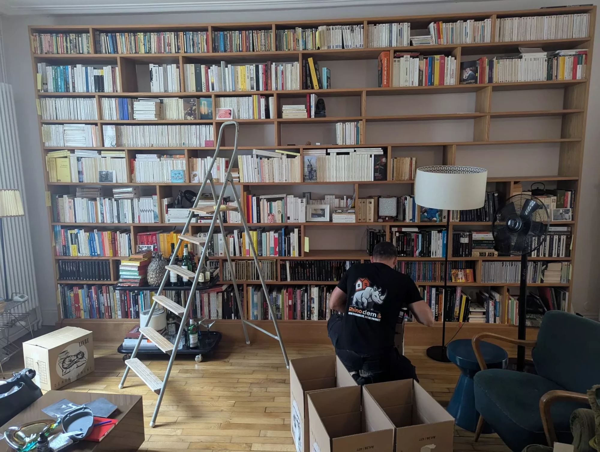 Un déménageur met en carton les livres d'une bibliothèque