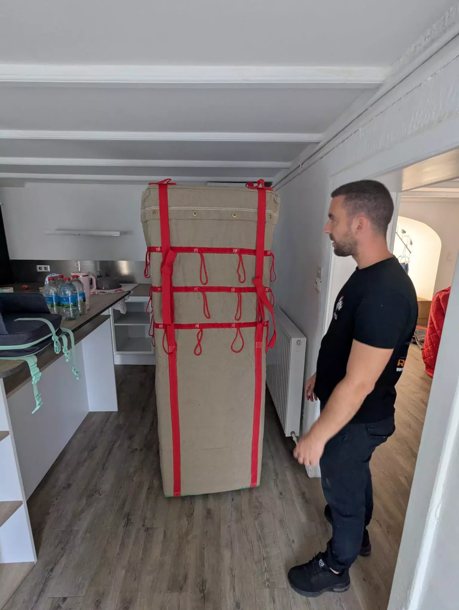 un déménageur à côté d'un frigo emballé dans une housse de déménagement