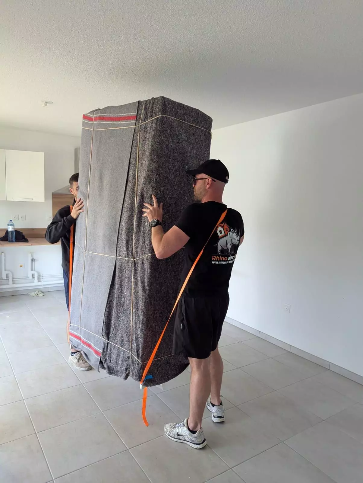 Deux déménageurs qui portent une armoire